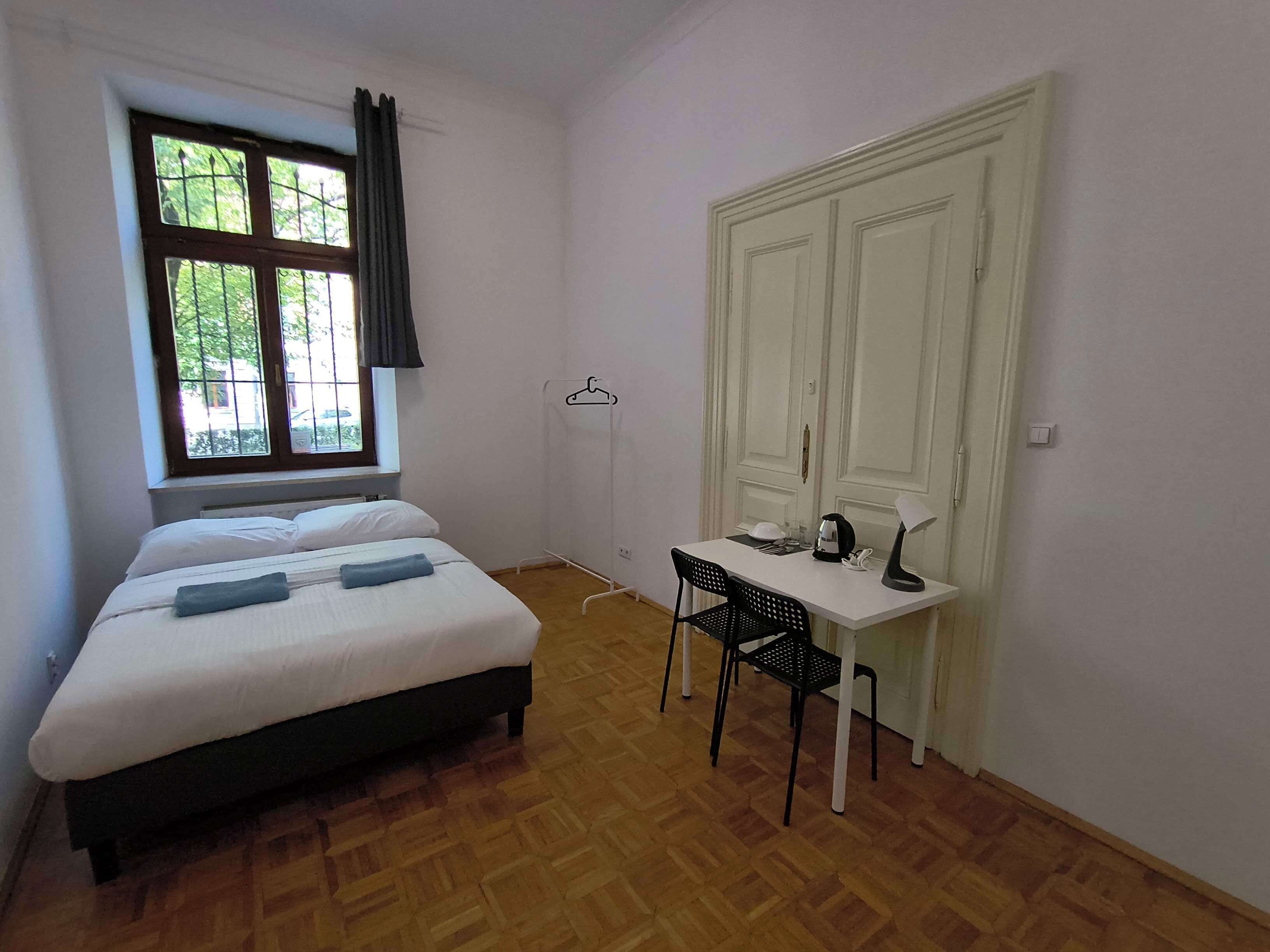 A room with a bed, a desk, a chair, and a wardrobe.