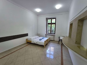 A room with a bed, a window, a radiator, and a small table.