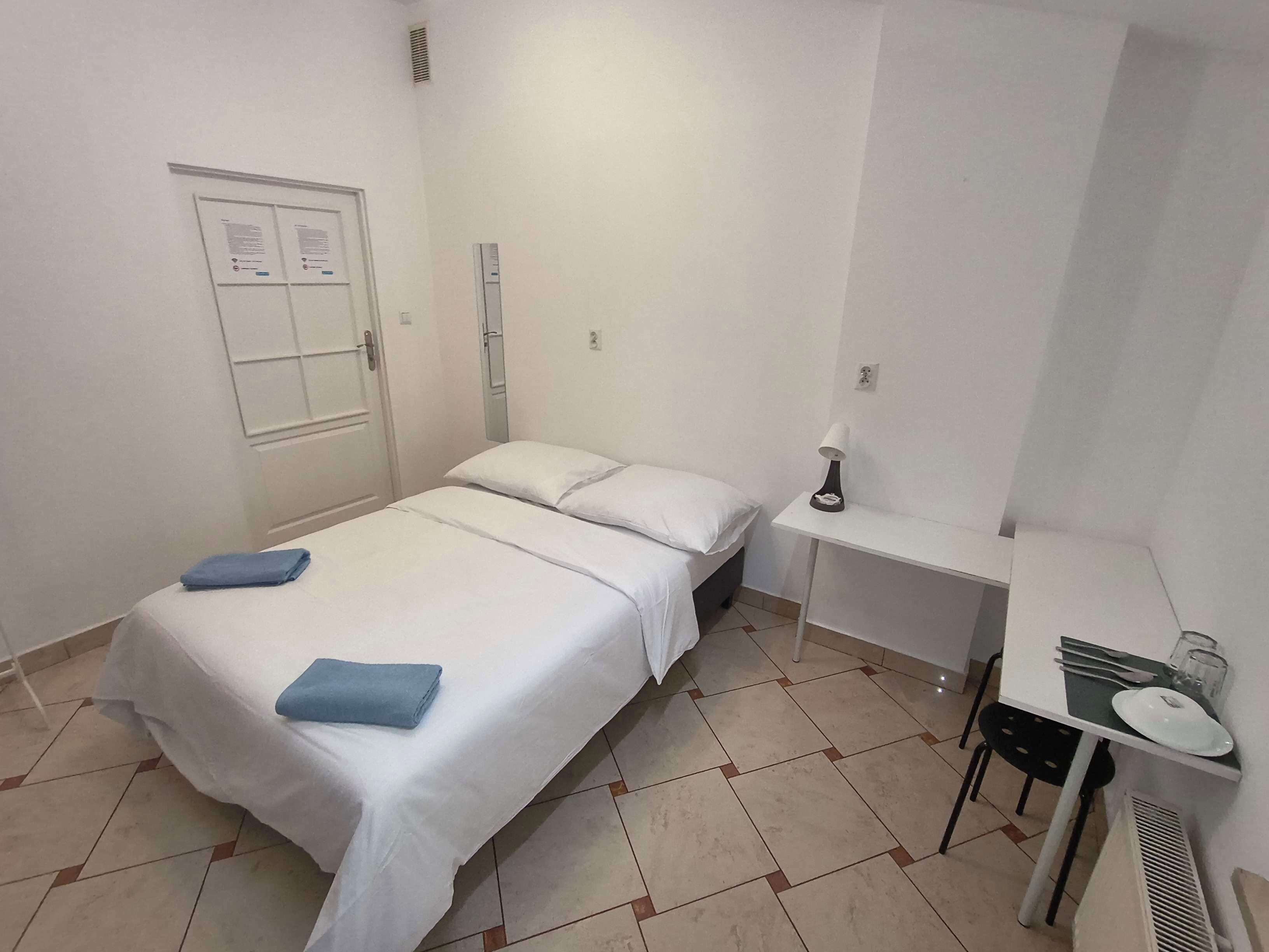 Une chambre à coucher avec un lit, une table de chevet avec une lampe et une petite table avec une assiette et des couverts.
