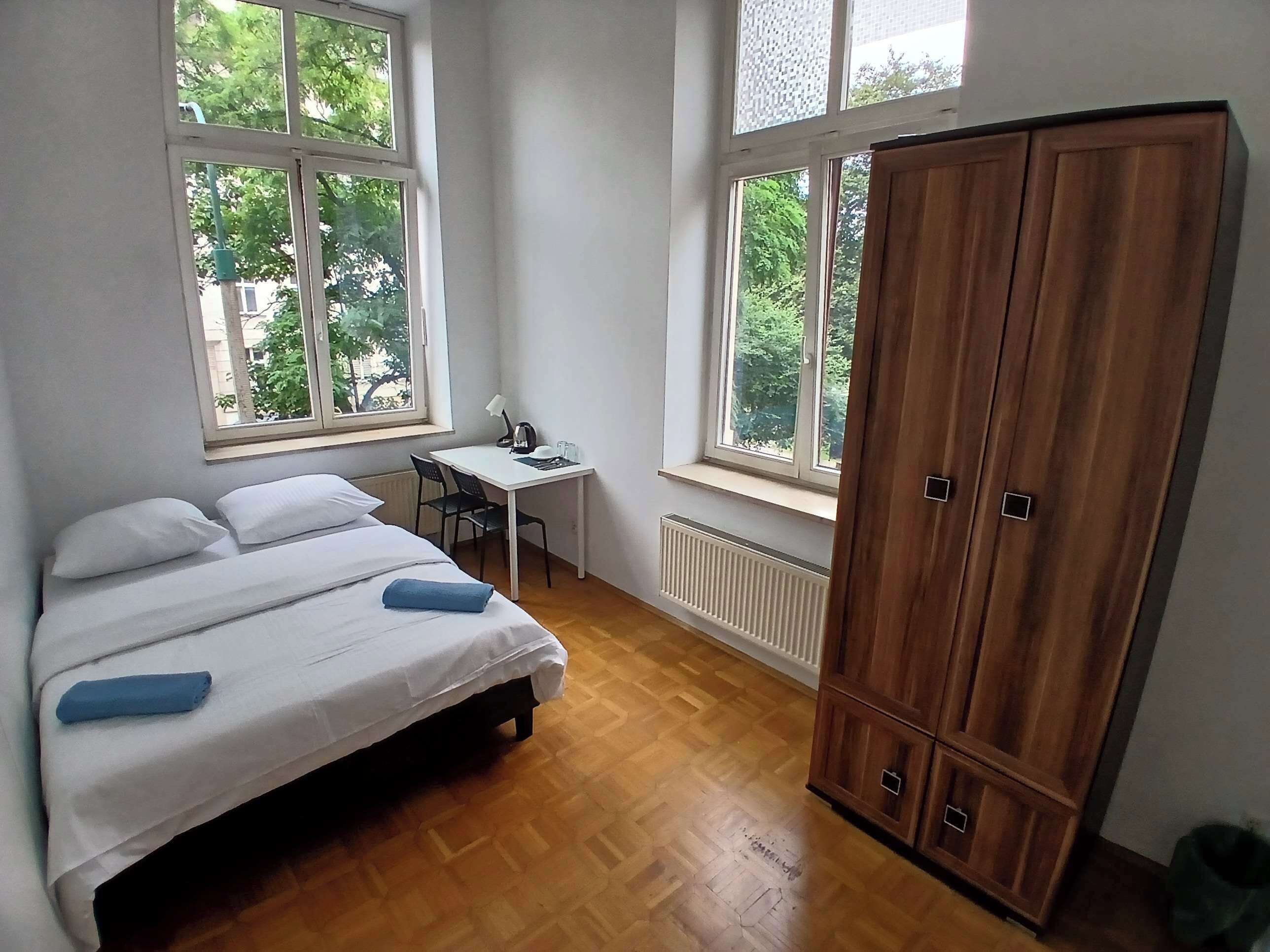 A bedroom with a bed, a desk, and a wardrobe.