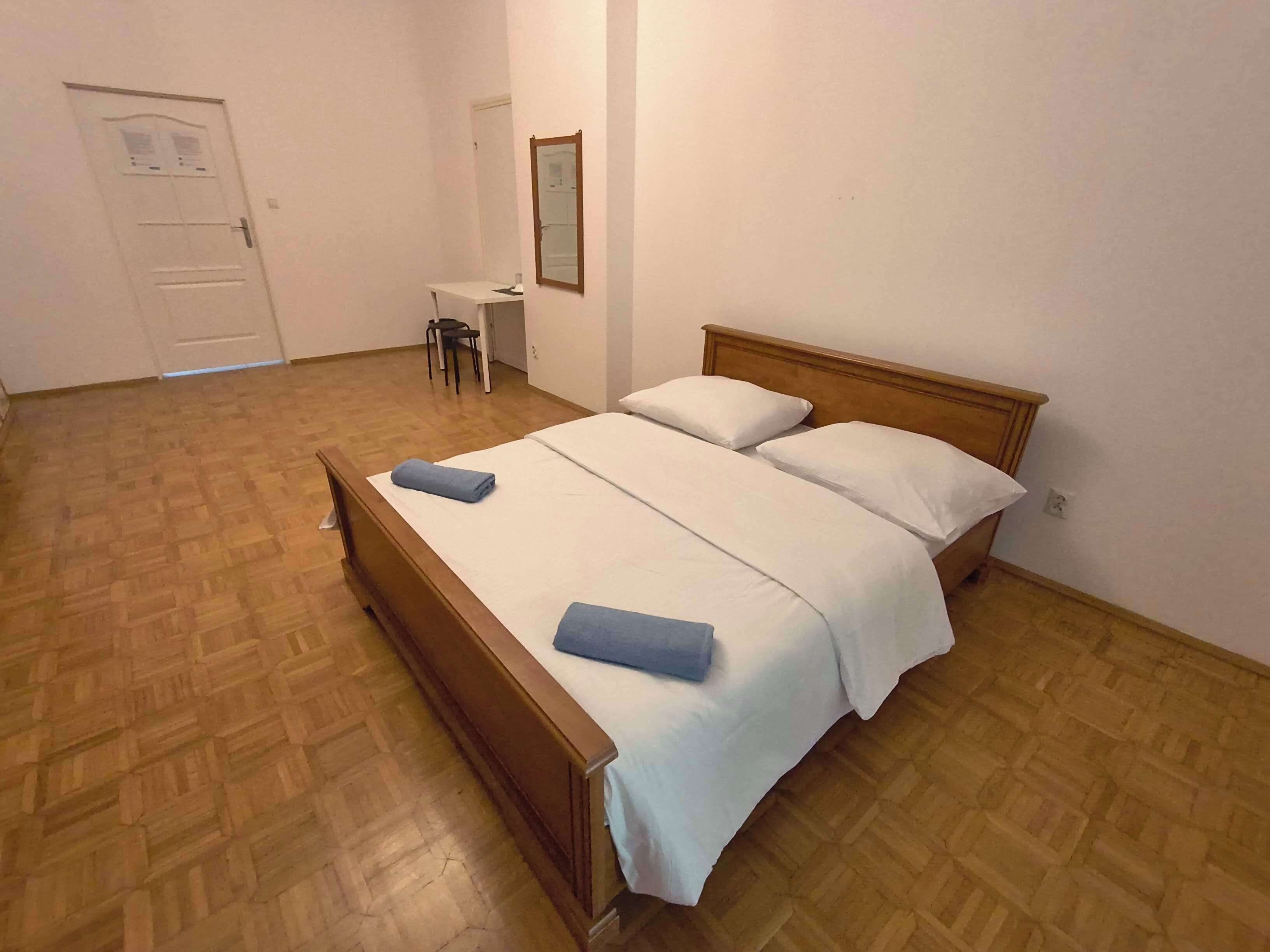 Une chambre à coucher avec un lit en bois, deux oreillers, un petit bureau et une chaise.