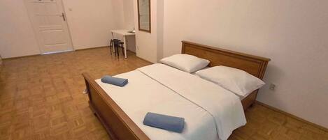 Une chambre à coucher avec un lit en bois, deux oreillers, un petit bureau et une chaise.
