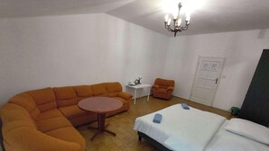 A room with a sofa, a small round table, a chair, a bed with two pillows, and a chandelier. - Fantastic Inn Kraków - B7 (Kraków)