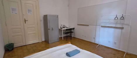 A room with a bed, a desk, a wardrobe, and a coat rack.