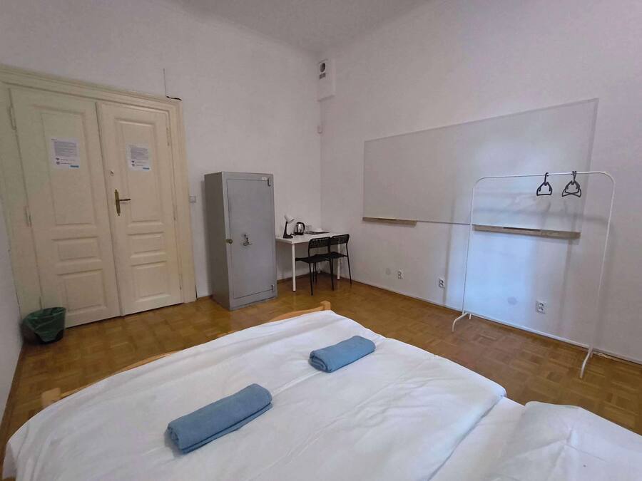 A room with a bed, a desk, a wardrobe, and a coat rack.