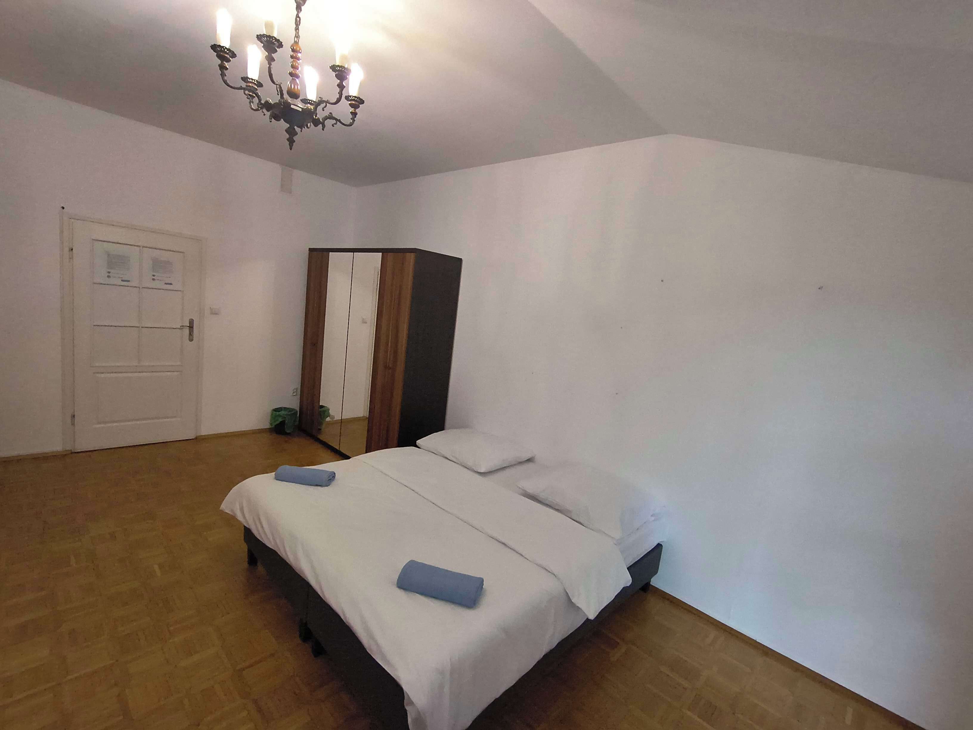 Ein Schlafzimmer mit einem Bett, einem Kleiderschrank, einer Chandelieber und einer Tür.