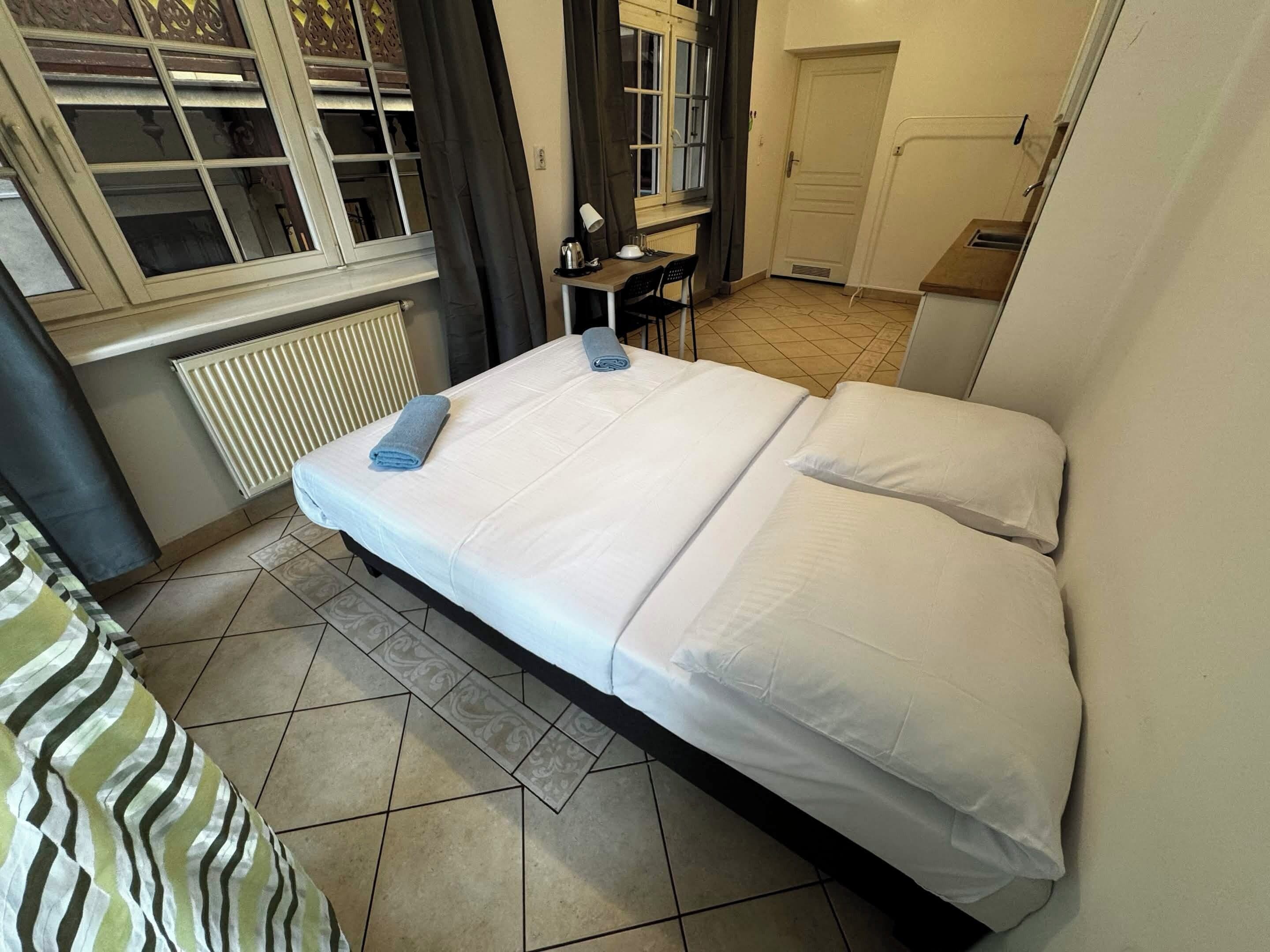 Un dormitorio con cama, escritorio, silla y radiador.