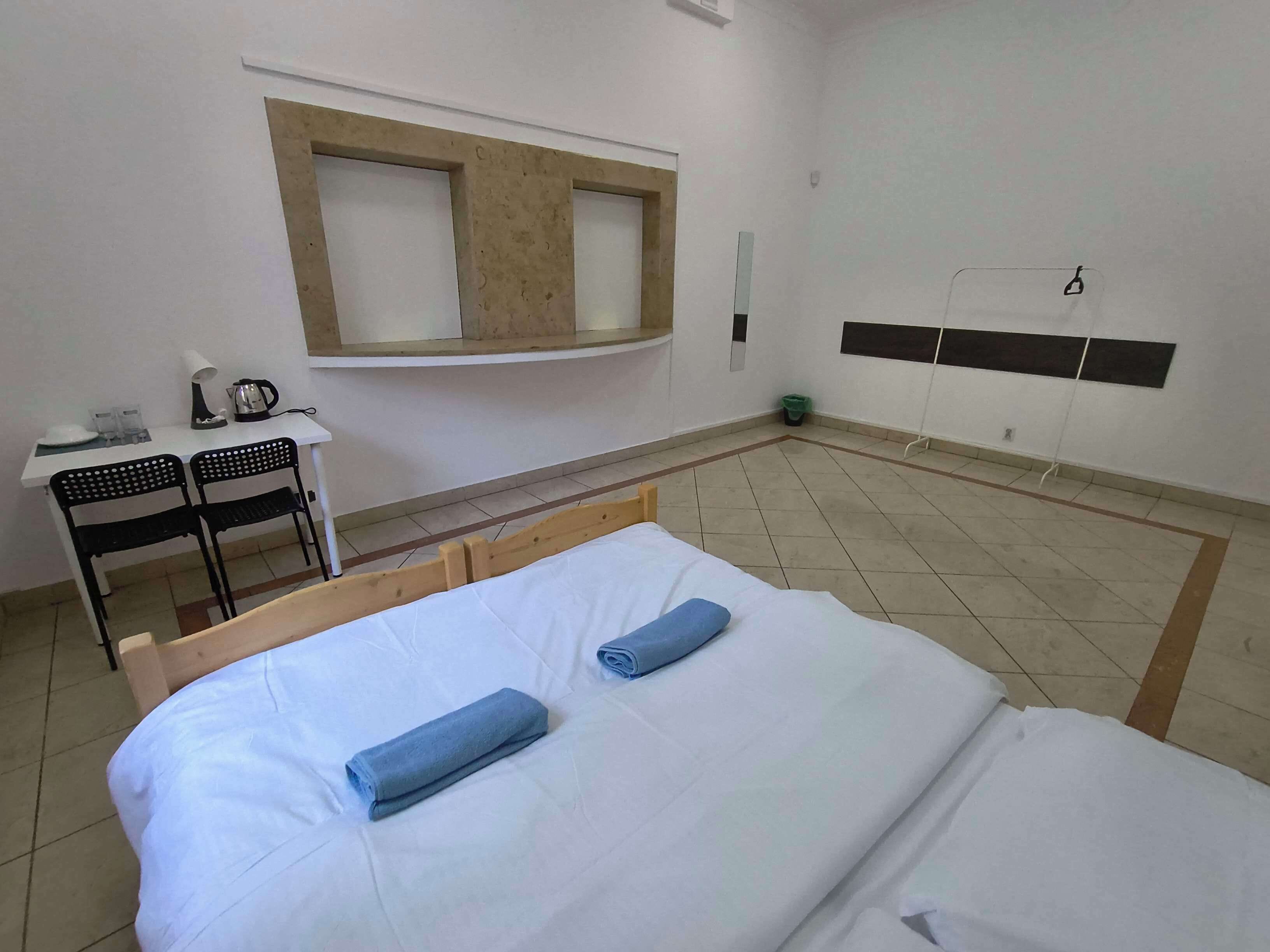 Habitación de hotel con cama, escritorio, silla, espejo y una ventana pequeña.