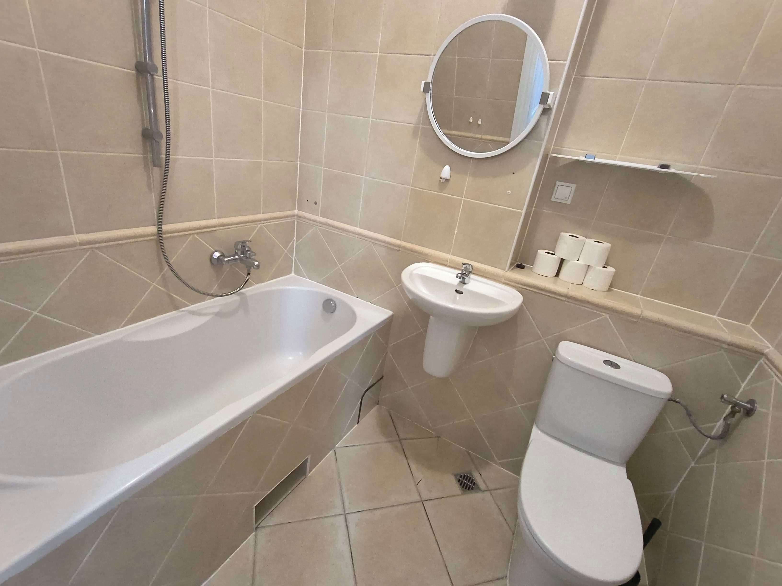 A bathroom with a bathtub, a sink, a toilet, and a mirror.