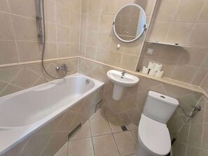 A bathroom with a bathtub, a sink, a toilet, and a mirror.