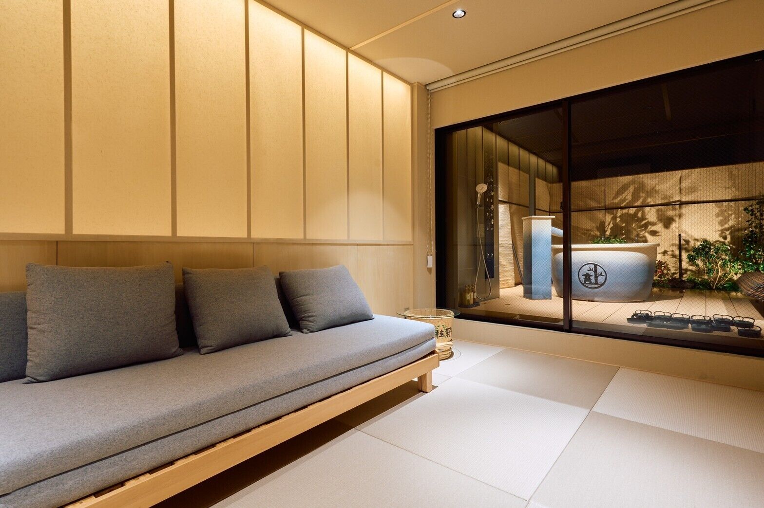 Un intérieur moderne avec un canapé, une grande fenêtre et une vue sur une pièce de style japonais traditionnel.