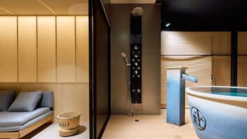 A modern bathroom with a bathtub, a shower area, and a seating area with cushions.