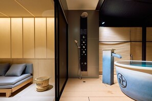 Un baño moderno con bañera, zona de ducha y rincón de descanso con cojines.