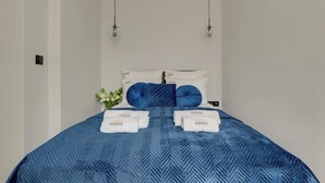 Una camera d'albergo con un letto, due lampadari a sospensione e un pannello di controllo fissato al muro.