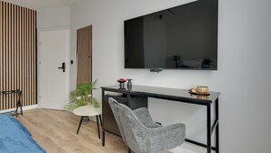 Ein modernes Schlafzimmer mit Bett, Schreibtisch mit Stuhl, Fernseher und Kleiderschrank.