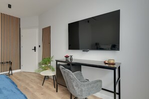 Ein modernes Schlafzimmer mit Bett, Schreibtisch mit Stuhl, Fernseher und Kleiderschrank.