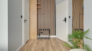 A hallway with wooden flooring, white walls, and a vertical striped wall design. - Lawendowa Room Nº3 | Shared Kitchen | Old Town (Gdańsk)