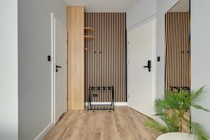 A hallway with wooden flooring, white walls, and a vertical striped wall design. - Lawendowa Room Nº3 | Shared Kitchen | Old Town (Gdańsk)