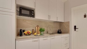 A modern kitchen with white cabinets, a microwave, a kettle, and a fruit bowl. - Lawendowa Room Nº3 | Shared Kitchen | Old Town (Gdańsk)
