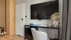 Ein modernes Zimmer mit Schreibtisch, Stuhl, Fernseher und einer dekorativen Vase.