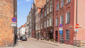 Una calle estrecha flanqueada por edificios históricos, algunos con balcones y señalización que indica restricciones de estacionamiento y acceso vehicular.