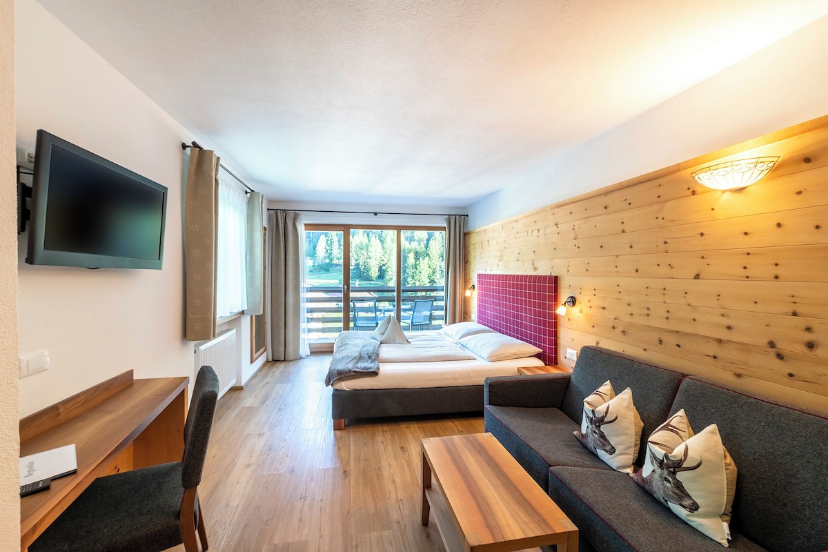 A modern room with a bed, sofa, and a TV mounted on the wall.