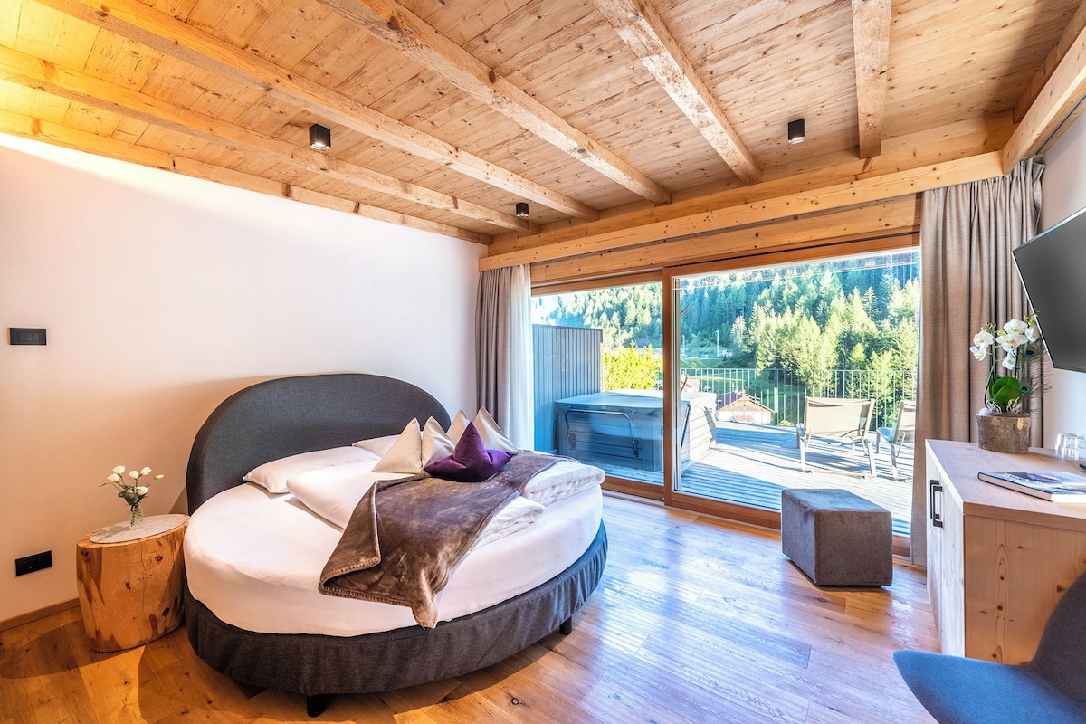 A bedroom with a bed, a desk, a window, and a view of the outdoors.