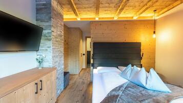 Ein Schlafzimmer mit einem Bett, einem Holzkopfende, einem an der Wand montierten Fernseher und einem Holzboden.