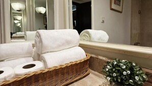 Un baño con un espejo grande, una cesta de mimbre con toallas, una planta en maceta y una zona de ducha.