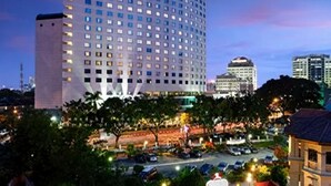 Un edificio de hotel de varios pisos con un letrero llamativo que dice 'Hotel Royal', rodeado de un estacionamiento y otros edificios.
