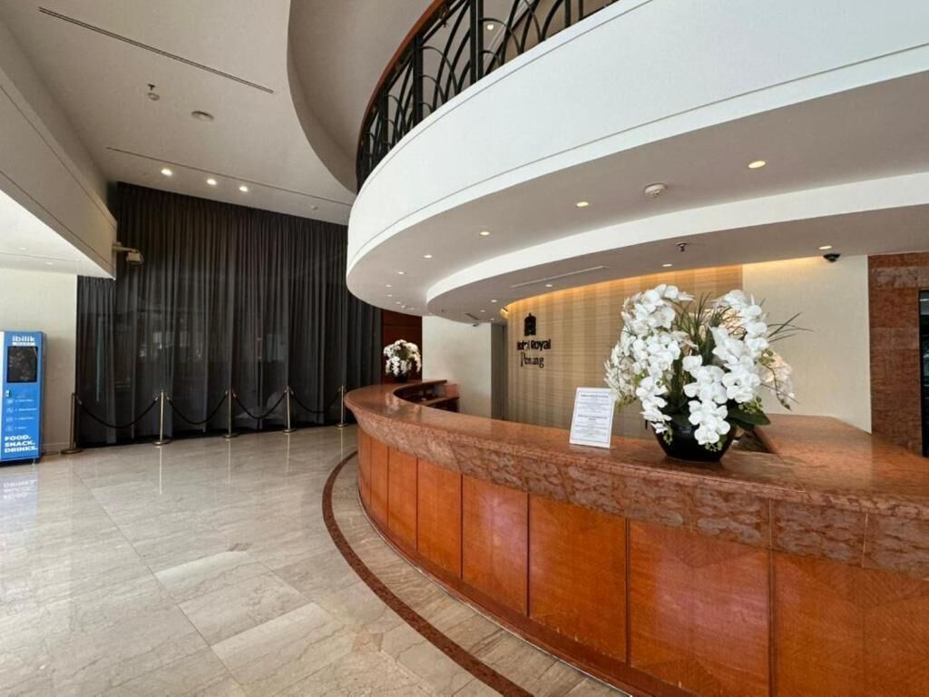 A hotel reception area with a curved reception desk, a security desk, and a staircase.