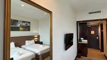 A hotel room with two beds, a large mirror, a painting on the wall, and a television.