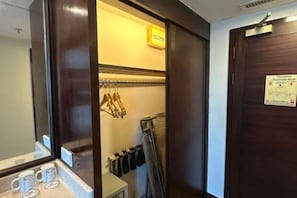 Habitación de hotel con puerta de madera, un espejo, toallero y una mesita con taza y platillo.