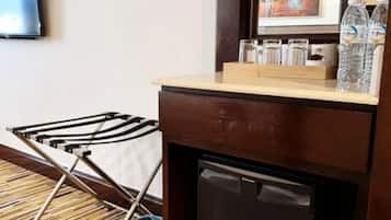 A compact room with a small refrigerator, a wooden counter, and a folding chair.