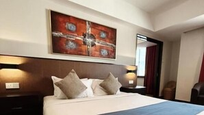 Habitación de hotel con una cama grande, cabecera, obra de arte en la pared y piso alfombrado.