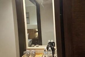 Una habitación de hotel con un espejo grande, una mesita de noche con artículos de aseo y una cama.