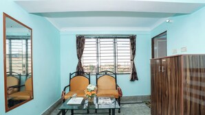 A room with two chairs, a table, a mirror, and a wardrobe. - Metro Stay Guest House (Barasat)