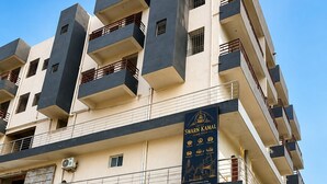 Un edificio de varios pisos con un letrero que indica 'Swarn Kamal' y servicios 'Classic Stay'.
