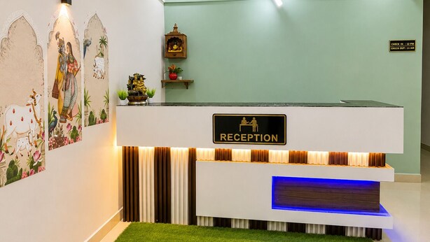 Zona de recepción con un cartel que indica 'RECEPTION', una lámpara fijada a la pared y una pequeña estantería con objetos decorativos.