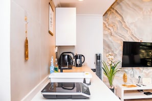 Una cocina moderna con cafetera, hervidor y microondas integrados.