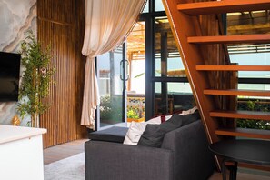 Un interior moderno con sofá, televisor y vistas al exterior.