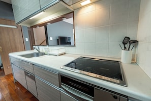 A modern kitchen with a built-in stove, oven, and sink. - Komachi House (Chatan)