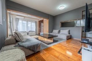 A modern living room with a sofa set, a coffee table, and a television. - Komachi House (Chatan)