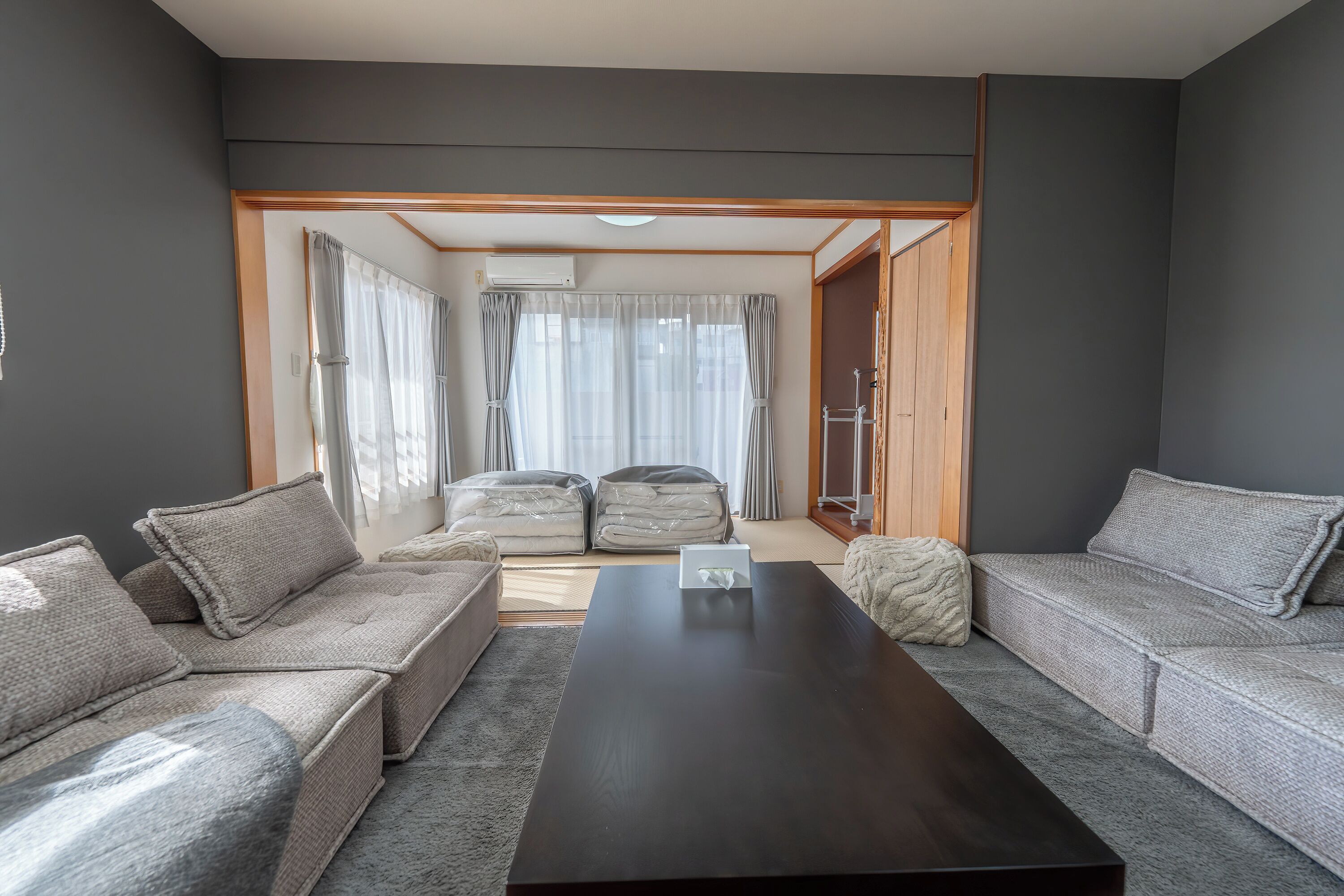 A modern living room with a sofa set, a coffee table, and a view through a doorway to a balcony.