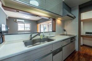 A modern kitchen with a stainless steel sink, a built-in oven, and a dishwasher. - Komachi House (Chatan)