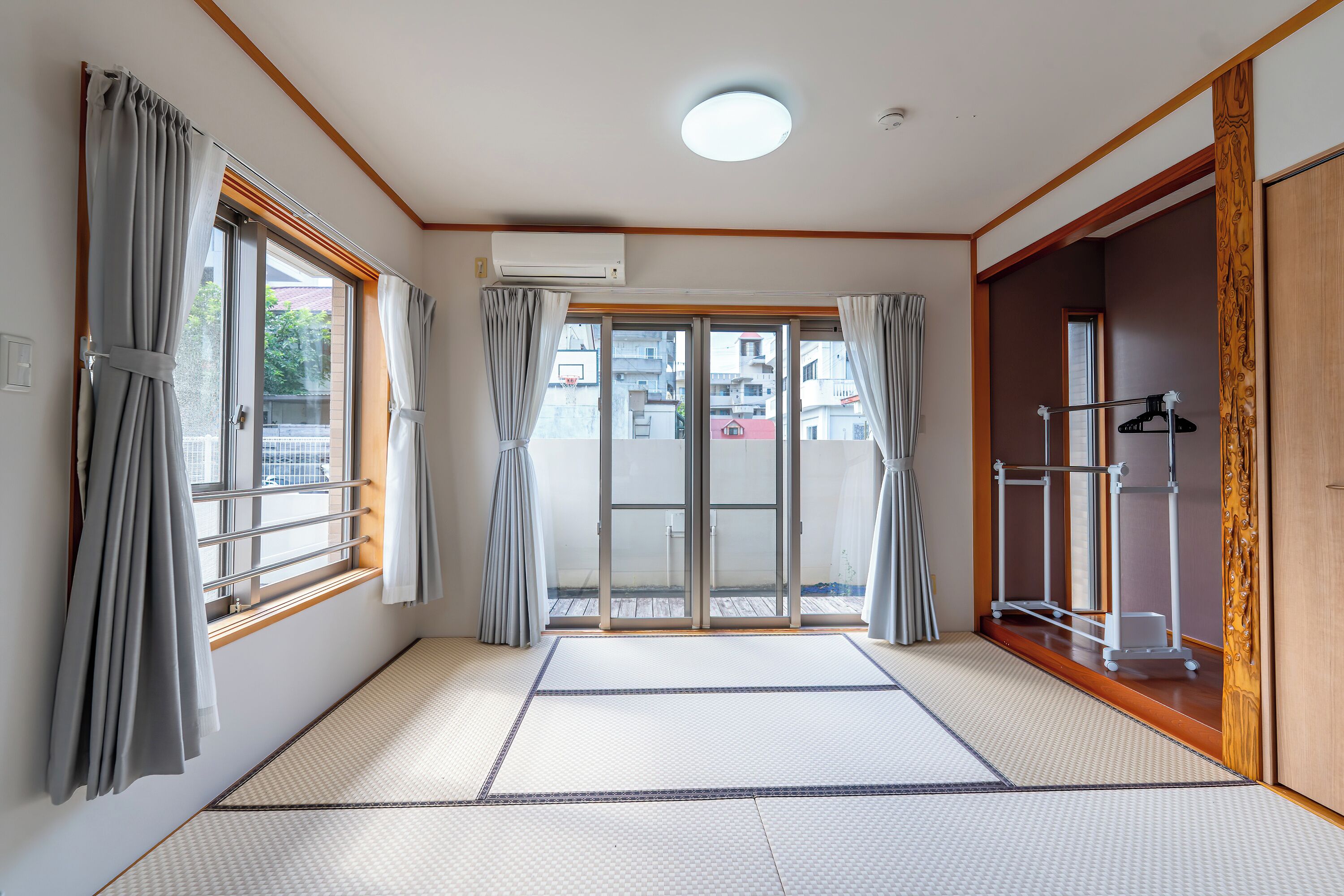 A room with a sliding glass door leading to an outdoor area, a ceiling-mounted air conditioner, and a wooden door with a decorative panel.