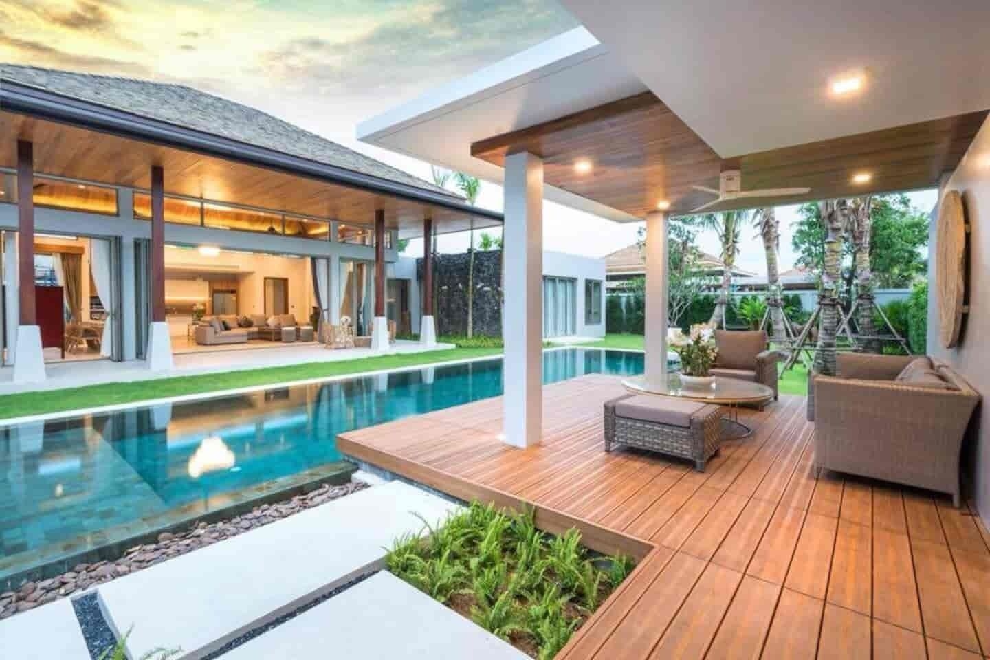 A modern house with a swimming pool, outdoor furniture, and a patio area.