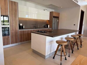 A modern kitchen with a central island, bar stools, and built-in appliances.