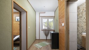 A compact room with a bed, a small table, a black cabinet, and a window with a curtain.