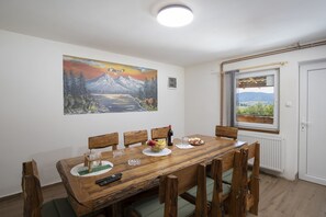 Un comedor con una mesa de madera, sillas, un cuadro y una ventana con vistas.